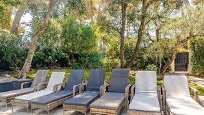A row of wicker lounge chairs with cushions, arranged on a stone patio surrounded by trees. - Stylish, Contemporary Villa heated pool, 10 mins walk to Beach  (Antibes)