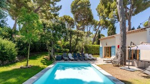 A swimming pool with lounge chairs, surrounded by trees and a building with a tiled roof. - Stylish, Contemporary Villa heated pool, 10 mins walk to Beach  (Antibes)