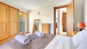A bedroom with a bed, a wardrobe, a mirror, a dresser, and a door leading to a closet. - Stylish, Contemporary Villa heated pool, 10 mins walk to Beach  (Antibes)