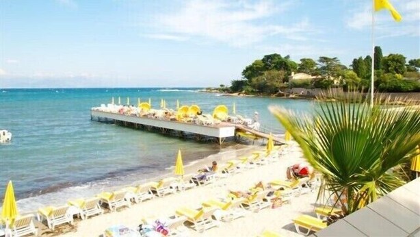 A beach with sun loungers and umbrellas, a pier extending into the water, and a flag on a flagpole. - Stylish, Contemporary Villa heated pool, 10 mins walk to Beach  (Antibes)