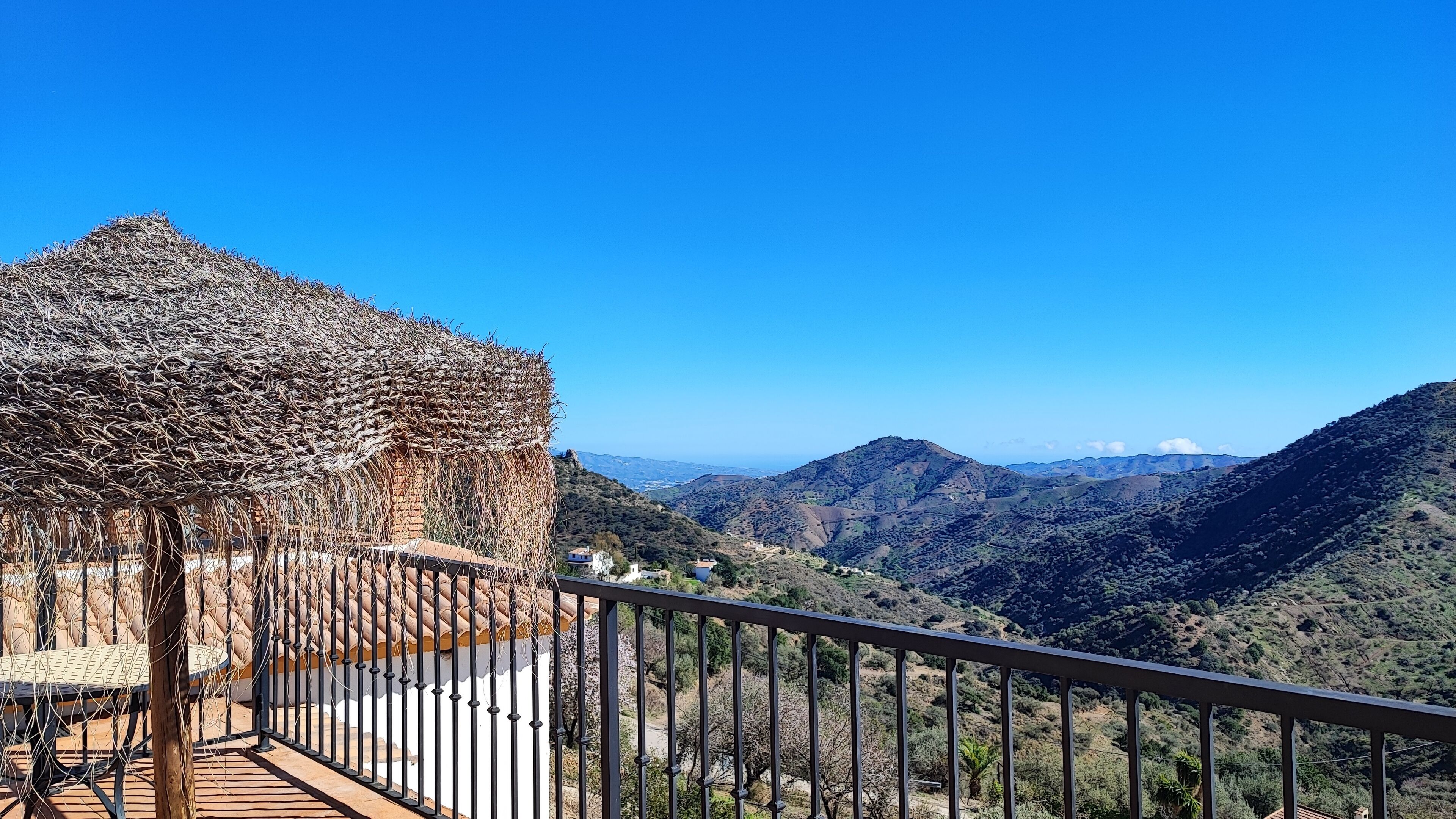 Una terrazza con copertura in paglia che si affaccia su un paesaggio montuoso.