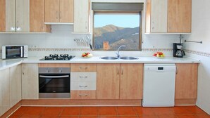 A kitchen with wooden cabinets, a gas stove, a dishwasher, and a window with a mountain view.