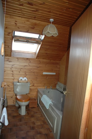 A small, wooden-paneled bathroom with a toilet, sink, and bathtub. - The Old Croft (Brora)