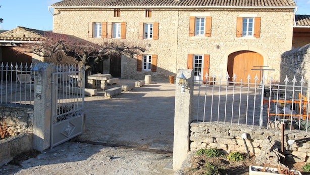 Un bâtiment en pierre doté d’une grande porte en bois et de nombreuses fenêtres.