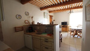 Une cuisine avec des poutres en bois, un évier, des placards et un coin repas comprenant des chaises et une table.