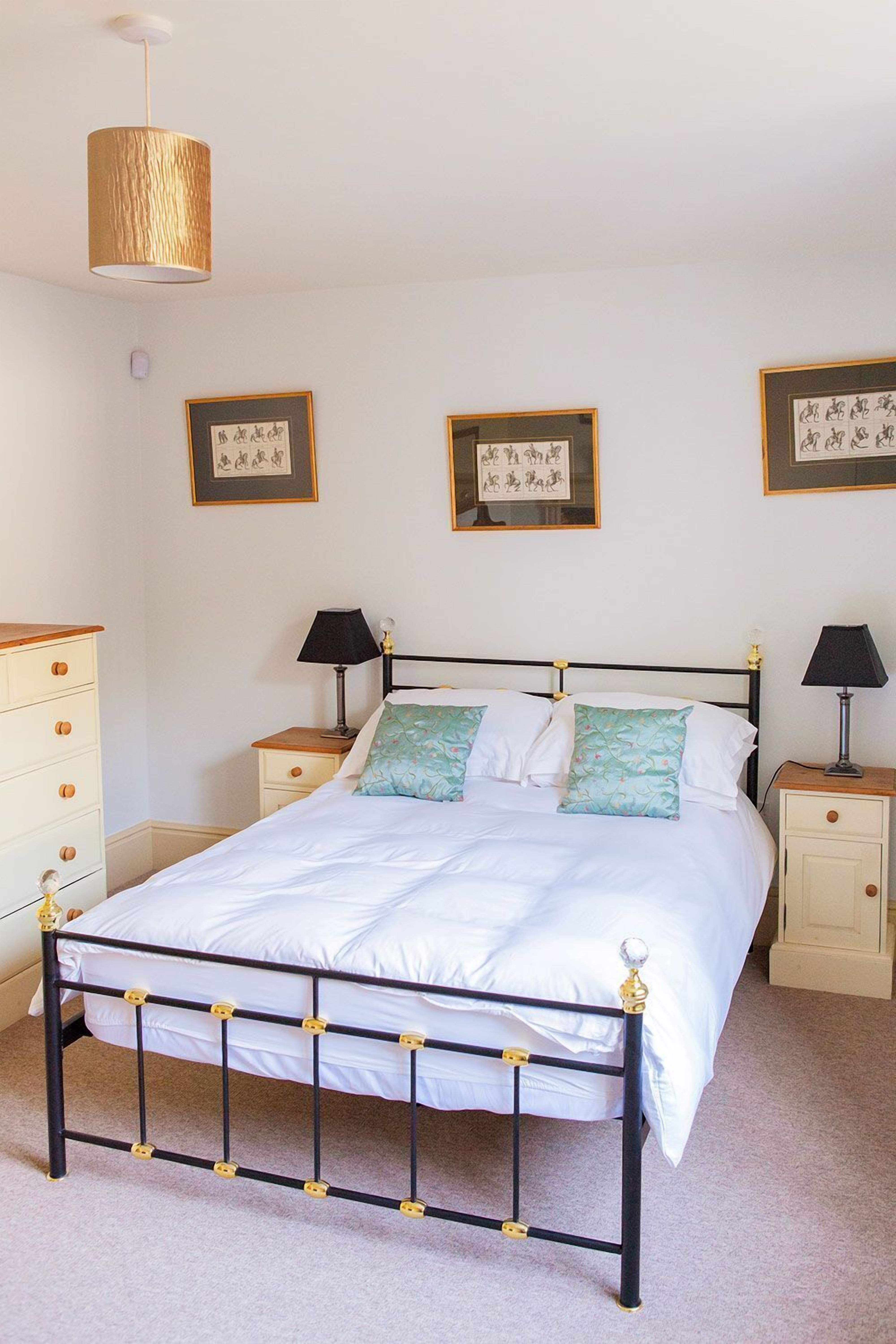 A neatly arranged bedroom with a bed, bedside tables, and framed pictures on the walls.