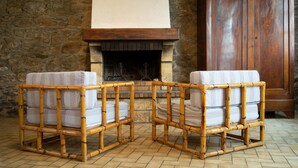 Une pièce avec un mur en pierre, un meuble en bois et deux fauteuils en osier dotés de coussins.