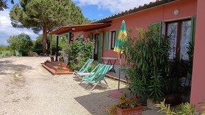 A house with a gravel driveway, outdoor seating, and potted plants. - Villa Giuliana, Three-room apartment 6/7 Ptl. (Capoliveri)