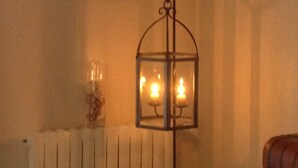 A room with a radiator, a hanging lantern with candles, and a colorful abstract painting on the wall.