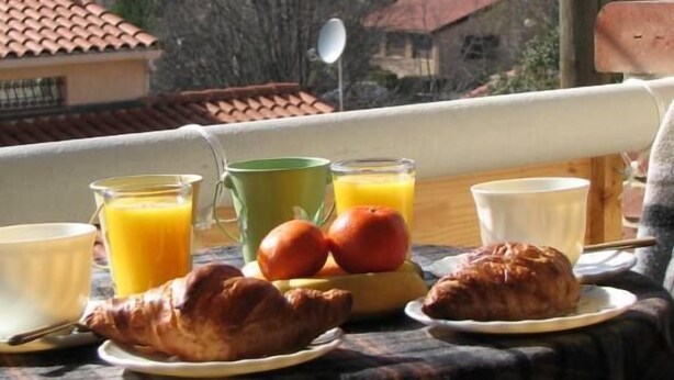 A table with breakfast items and a scenic view of a historic building and mountains.