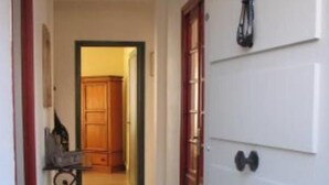 A hallway with a wooden door, a metal railing, and a tiled floor.
