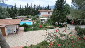 Ein Wohngebiet mit einem Schwimmbad, einem kleinen Haus mit Ziegeldach und einem Garten mit roten Blumen.
