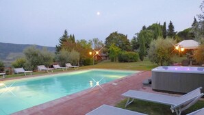 A swimming pool with lounge chairs and a hot tub, surrounded by trees and a brick patio. - Independent villa in the panoramic countryside (Greve In Chianti)