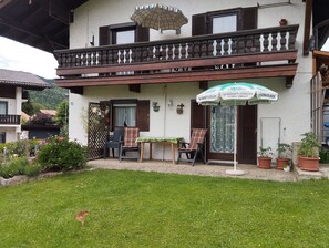 A two-story building with a balcony, outdoor seating, and potted plants. - Nice apartment at ground level in Ruhpolding, children and pets are welcome (Bayern)