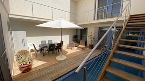 A residential balcony with a pool, outdoor furniture, and a staircase.