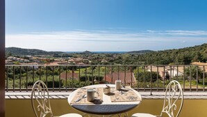 Ein Balkon mit Tisch und Stühlen, der einen schönen Ausblick auf eine Landschaft mit Häusern und Hügeln bietet.