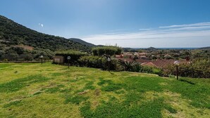 Ländliche Landschaft mit einer Wiese, einem kleinen Gebäude und einem fernen Dorf mit roten Dächern.