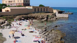 A coastal hotel with a sandy beach, rocky shoreline, and clear blue sea. - 100 meter from the sea, nice apartment in centre of Alghero with terrace  (Alghero)
