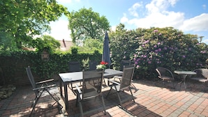 An outdoor patio with a brick floor, a table with chairs, and a small round table with chairs. - 4 * holiday on the canal in Nordgeorgsfehn (East Frisia) (Uplengen)
