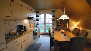 A kitchen with white cabinets, a wooden countertop, and a dining area with a table and chairs. - 4 * holiday on the canal in Nordgeorgsfehn (East Frisia) (Uplengen)