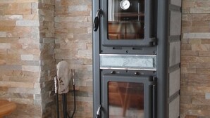 A wood-burning stove with a glass door, a thermometer, and a chimney pipe. - Luxurious and large apartment (103 m²) at 1,735 m with underground parkin (Haute Nendaz / Siviez)