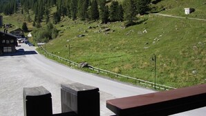 A road leading to a building with a parking area and a mountainous backdrop. - Luxurious and large apartment (103 m²) at 1,735 m with underground parkin (Haute Nendaz / Siviez)