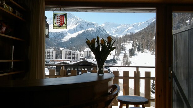 A view from a balcony with a vase of flowers, a wooden railing, and a mountain backdrop. - Luxurious and large apartment (103 m²) at 1,735 m with underground parkin (Haute Nendaz / Siviez)