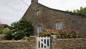 Una casa de piedra con un portón blanco, una ventana pequeña y un letrero con el número 20.