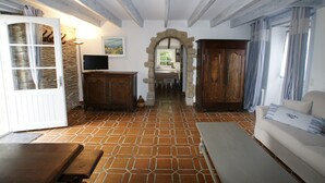 Amplia sala de estar con piso de baldosas, un banco de madera, un sofá y un televisor sobre un mueble de madera.