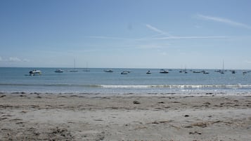 Une plage avec des bateaux ancrés dans l’eau et un rivage sablonneux.