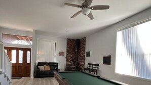 A pool table in a room with a ceiling fan, a brick fireplace, and a window with blinds. - What a Great Escape for Families  and Friends!   Private Slip! (Lake Nacimiento)