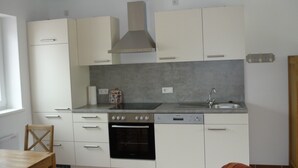 A compact kitchen with white cabinets, a stainless steel sink, and a built-in oven.