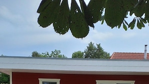 A red building with a white window, a bench, and a white chair outside.