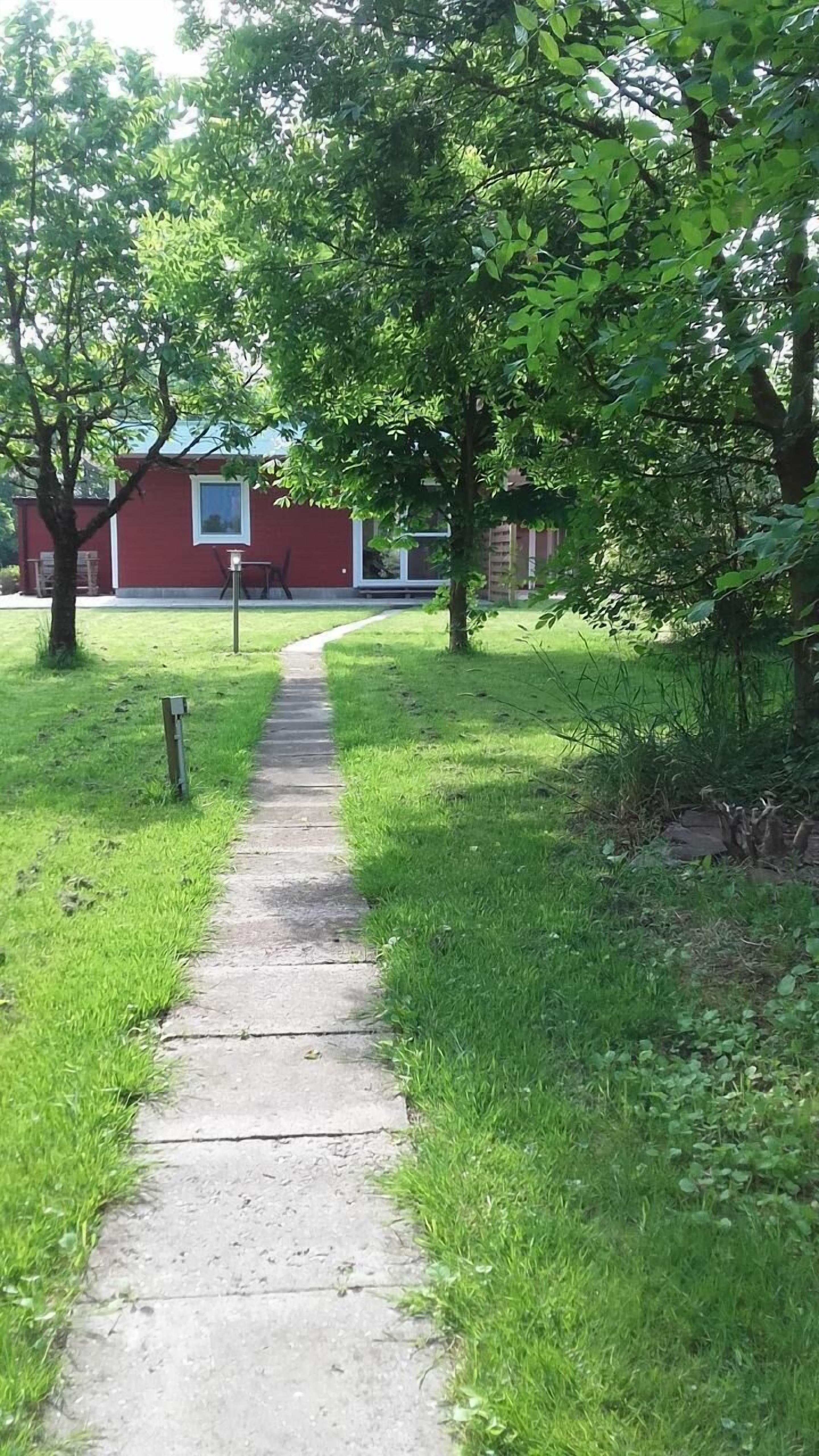A concrete pathway leading to a red building with a window.