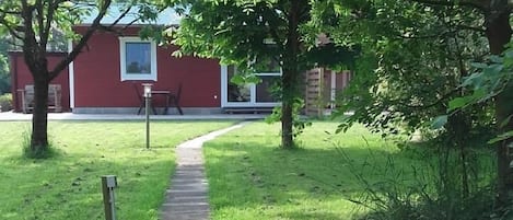 A concrete pathway leading to a red building with a window.