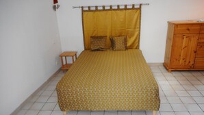 Une chambre à coucher avec un lit, une commode en bois et une petite table.