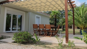 A covered patio with a table and chairs, a door, and a window. - Holiday home with private pool at the foot of the Pyrenees and near the beach (Laroque-Des-Albères)