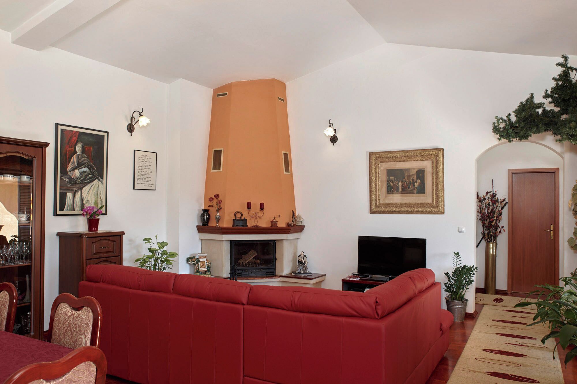 Un salon avec une cheminée, un canapé rouge et un téléviseur.