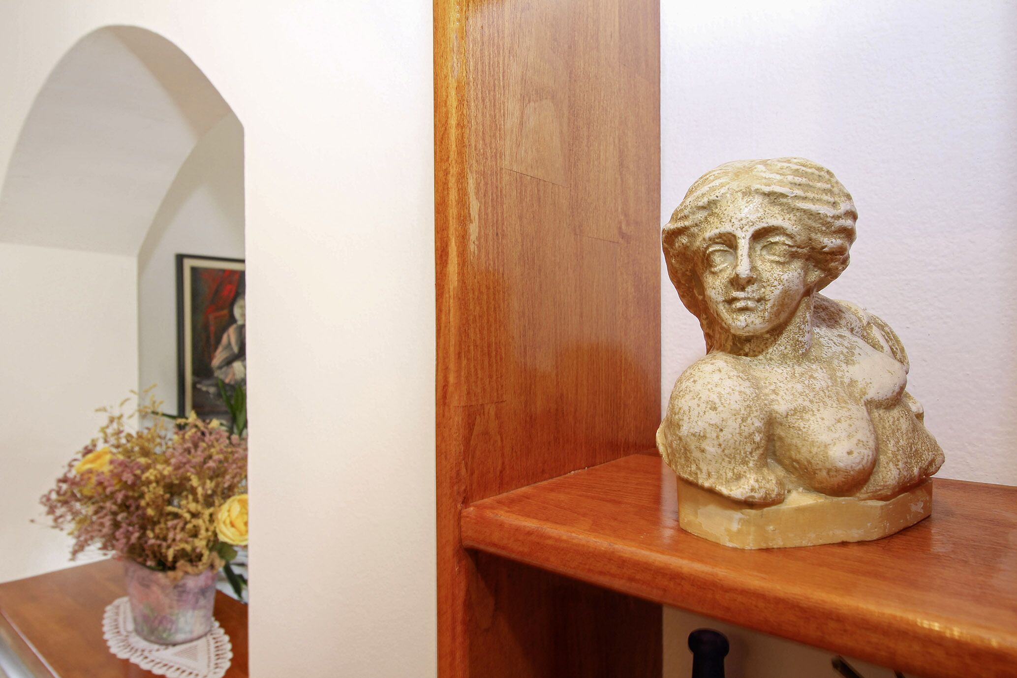 Una estantería de madera con una escultura de busto.