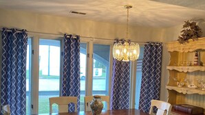 A dining area with a wooden table, chairs, a chandelier, and a kitchen island. -  Gorgeous sunsets and lake views (Port Clinton)