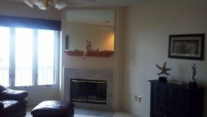 A living room with a fireplace, a sofa, and a cabinet with decorative items. -  Gorgeous sunsets and lake views (Port Clinton)