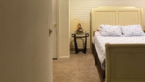 A bedroom with a bed, a small table, and a wall-mounted shelf. -  Gorgeous sunsets and lake views (Port Clinton)