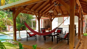 A wooden deck with a hammock, outdoor furniture, and a pool. - Villa Emeraude - Superb Creole villa with amazing Pool & direct access to beach (Diamant)