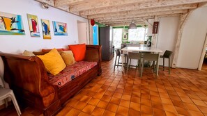 Uma sala de estar aconchegante com um sofá de madeira, almofadas coloridas e piso de azulejos.