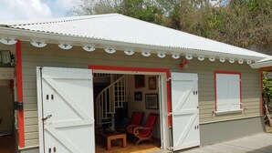 A house with two open white doors leading to a wooden interior with red chairs and a staircase. - Villa Emeraude - Superb Creole villa with amazing Pool & direct access to beach (Diamant)