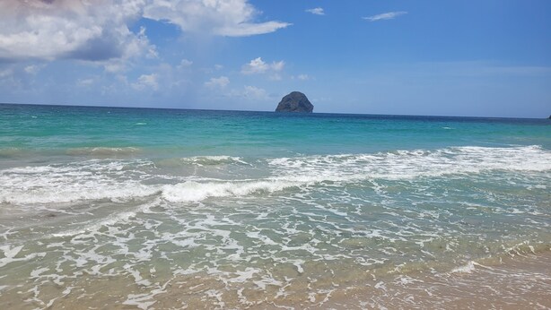 A beach with clear turquoise water and a distant rocky outcrop. - Villa Emeraude - Superb Creole villa with amazing Pool & direct access to beach (Diamant)
