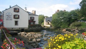 A white building with a sign reading "Boulain du Grand Boulain" and a river in the foreground.
