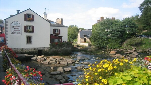 A white building with a sign reading "Boulain du Grand Boulain" and a river in the foreground.