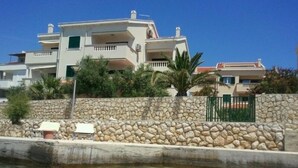 A coastal property with a stone wall, a pool, and a clear view of the sea.