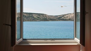 A window with a view of a calm body of water and hills in the distance.